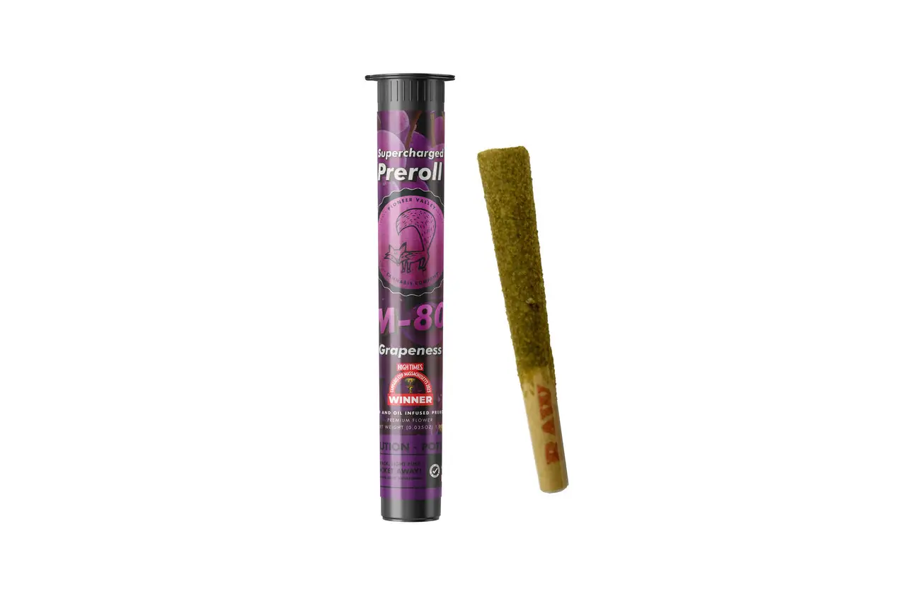An M-80 Grapeness infused pre-roll in its printed tube, the pre-roll laid alongside it.