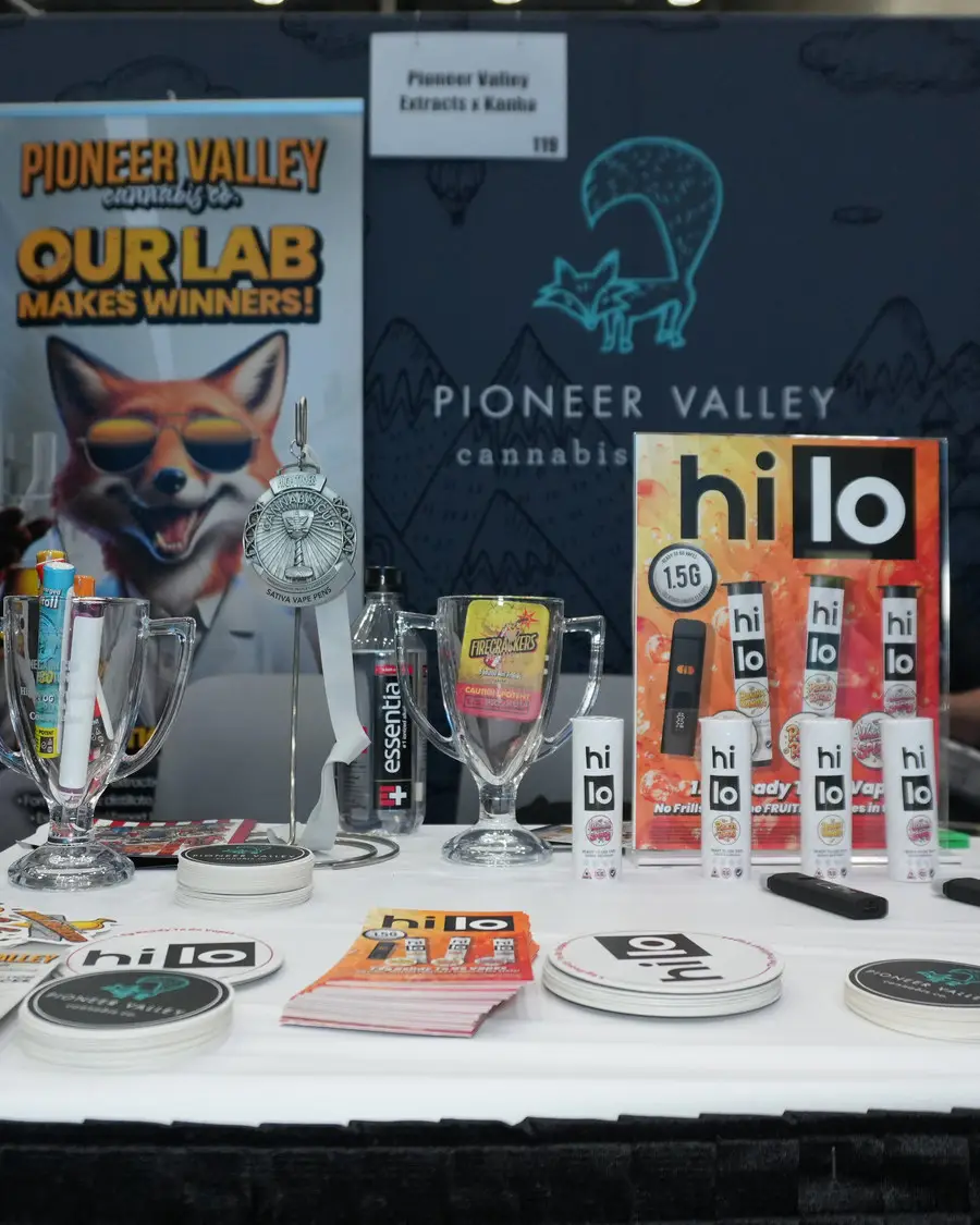 The Pioneer Valley Extracts and Kanha trade-show booth, portrait crop, showing the Our Lab Makes Winners banner above the laid-out product table.